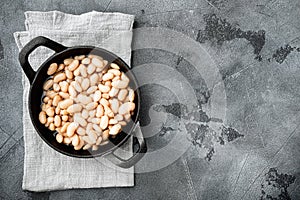 White kidney beans, in cast iron frying pan, on gray stone background, top view flat lay, with copy space for text