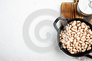 White kidney beans, in cast iron frying pan, on white stone  surface, top view flat lay, with copy space for text