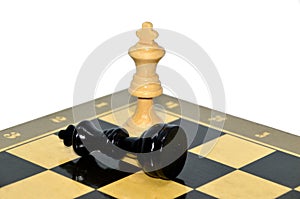 The white king defeated black king on chess board isolated on white background. Blurred black king