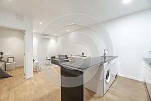 white kitchen with black countertops and white appliances, hardwood