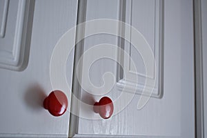 White kitchen cabinet with red knobs