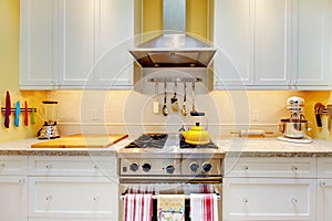 WHite kitchen cabinets with stove and hood.