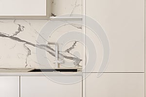 White kitchen faucet in kitchen contemporary interior with creamy white furniture. Modern interior concept.