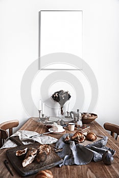White kitchen interior with breakfast on wooden table, poster on the white wall, space for design layout.