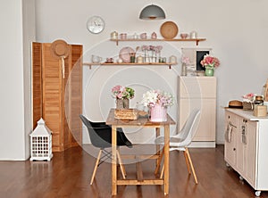 White kitchen interior in loft style. Shelves with pink crockery and kitchen utensils. Studio apartment. Rent and delivery of