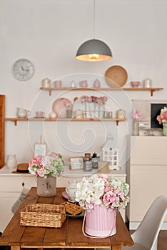 White kitchen interior in loft style. Shelves with pink crockery and kitchen utensils. Studio apartment. Rent and delivery of