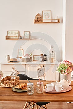 White kitchen interior in loft style. Shelves with pink crockery and kitchen utensils. Studio apartment. Rent and delivery of