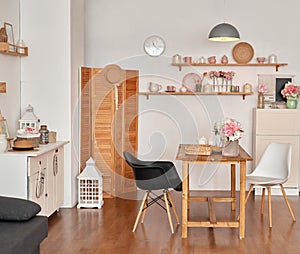 White kitchen interior in loft style. Shelves with pink crockery and kitchen utensils. Studio apartment. Rent and delivery of