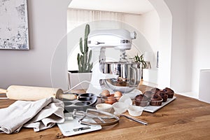 White kitchen machine and stand mixer on a wooden table in a bright design apartment