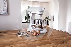 White kitchen machine and stand mixer on a wooden table in a bright design apartment