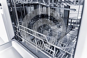 The white kitchen and opened dishwasher with clean dishes