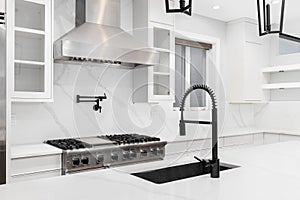 A white kitchen with stainless steel appliances and marble countertops.