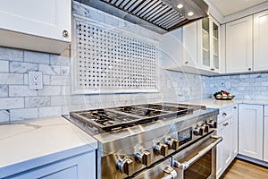 White Kitchen with stainless steel hood over gas cooktop.