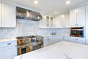 White Kitchen with stainless steel hood over gas cooktop.