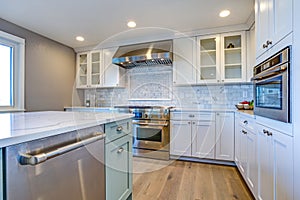 White Kitchen with stainless steel hood over gas cooktop.