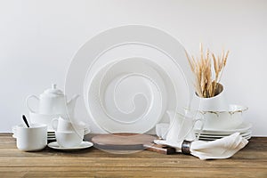 White kitchen utensils, dishware and other different white stuff for serving on white wooden board.