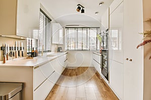 a white kitchen with white cabinets and a large window