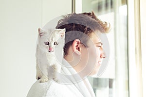 White kitten sitting on the man`s shoulder