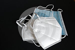 White KN95 or N95 mask with antiviral medical mask for protection against coronavirus on black background.