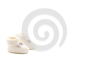 White knitted baby booties with bows on a gray isolated background
