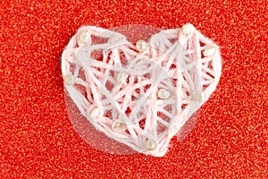 White knitted handmade heart on red glitter background. Happy Valentineâ€™s Day.