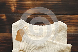 White knitted sweater with price tag on old wooden background top view. Fashion Lady Clothes Set Trendy Cozy Knit