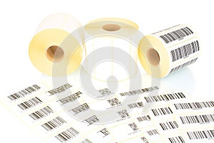 White label rolls and printed barcodes isolated on white background with shadow reflection. White reels of labels for printers.