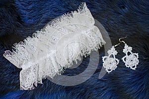 White lace bridal accessories on the fur blue background. Wedding garter on the texture background. fashion bridal earrings