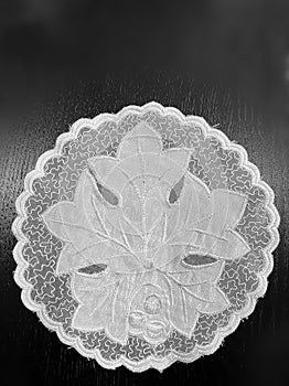 White lace doily on black background