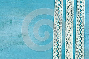 White lace ribbons on blue wooden background.