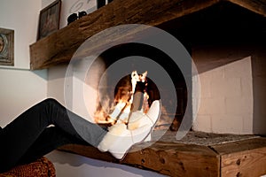 White lamb wool slippers houseshoes next to fireplace. Keep your feet warm and cozy during the freezing cold season