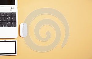 White laptop computer, tablet and mouse on yellow background