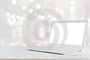 White laptop computer on wooden table over abstract lights background