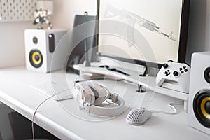 White large gaming headphones are on the table. Close-up in a bright interior