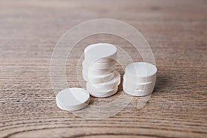 White large pills close up stand in a pile on a wooden background. Vitamins, pharmaceuticals for the treatment of diseases