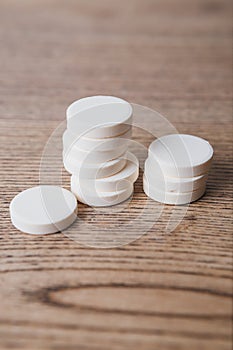 White large pills close up stand in a pile on a wooden background. Vitamins, pharmaceuticals for the treatment of diseases