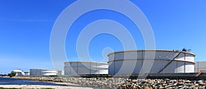 White large storage tanks under a blue sky.