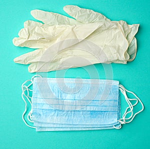 White latex gloves and disposable masks on a green background