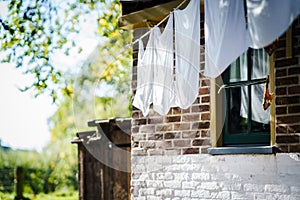White laundry hangs to dry at a vintage workers` cottage in a small dutch village