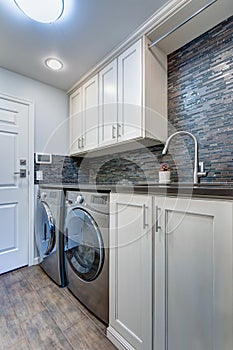 White laundry room boasts white shaker cabinets