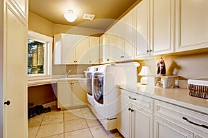 White laundry room interior with tile floor and cabinets.