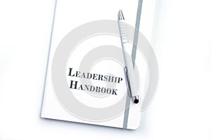 White Leadership Handbook or manual with White pen on a white table in an office.