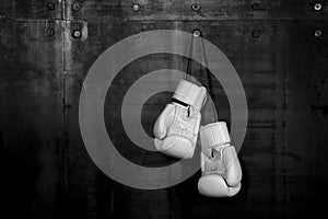 White leather boxing gloves hanging on black wall