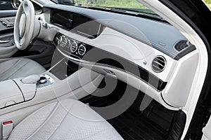 White leather interior of the luxury modern car. Leather comfortable white seats and multimedia. Steering wheel and dashboard.