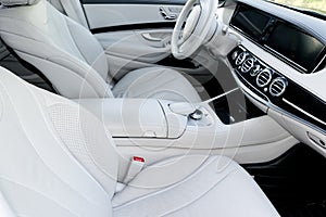 White leather interior of the luxury modern car. Leather comfortable white seats and multimedia. Steering wheel and dashboard.