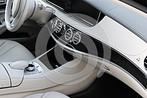 White leather interior of the luxury modern car. Leather comfortable white seats and multimedia. Steering wheel and dashboard.