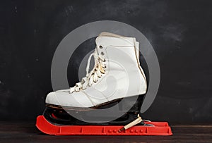 White leather skates for figure skating stand on a brown wooden background