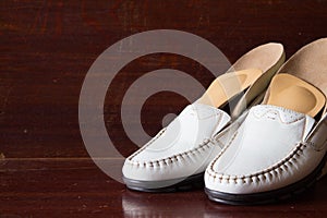 White leather slipper or shoes with orthopedic insoles. Wooden b