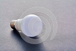 A white LED lamp with an E27 base lies on a gray background