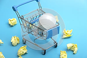 A white LED lamp in a supermarket cart against a background of crumpled notes. The concept of buying an idea. The franchisee